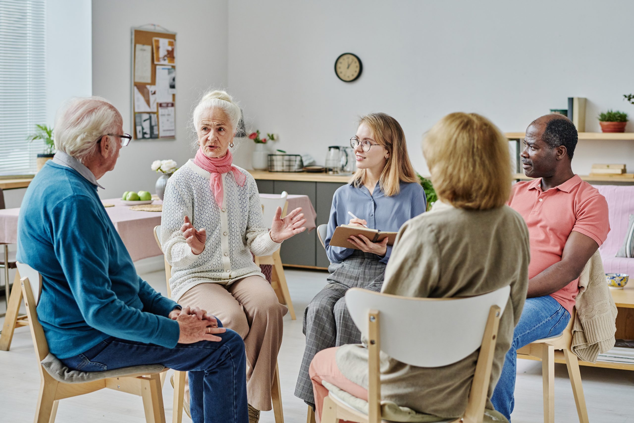 Group of senior people sitting on chairs and talking to each other during psychotherapy session